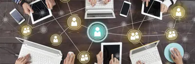 Photo from above of people sitting around in a meeting using technology