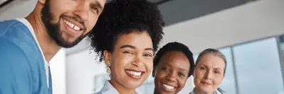 Group of four health care providers smiling at camera in a clinic.
